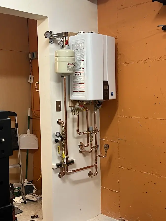 Plumbing technician inspecting water heater connections in Barrington
